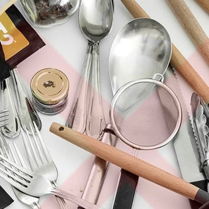 A kitchen drawer without dividers: cutlery, a sieve, tongs and sachets loose and overlapping