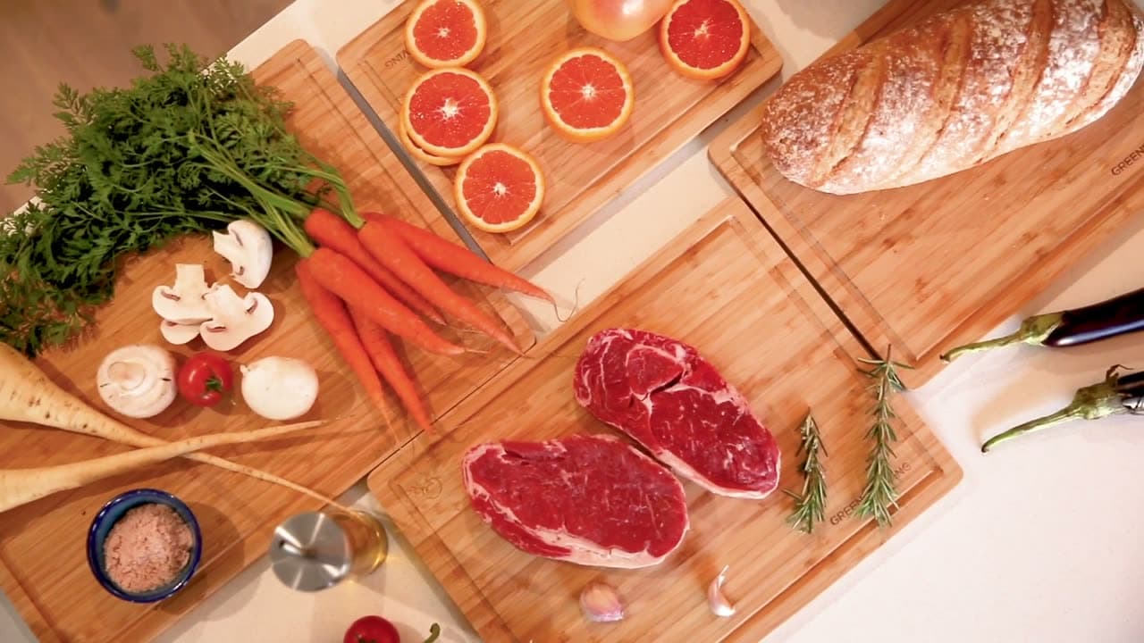 The three boards laid out with vegetables, bread and raw steak prepared separately