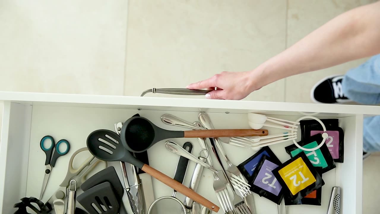 A cluttered kitchen drawer of loose utensils before the dividers go in