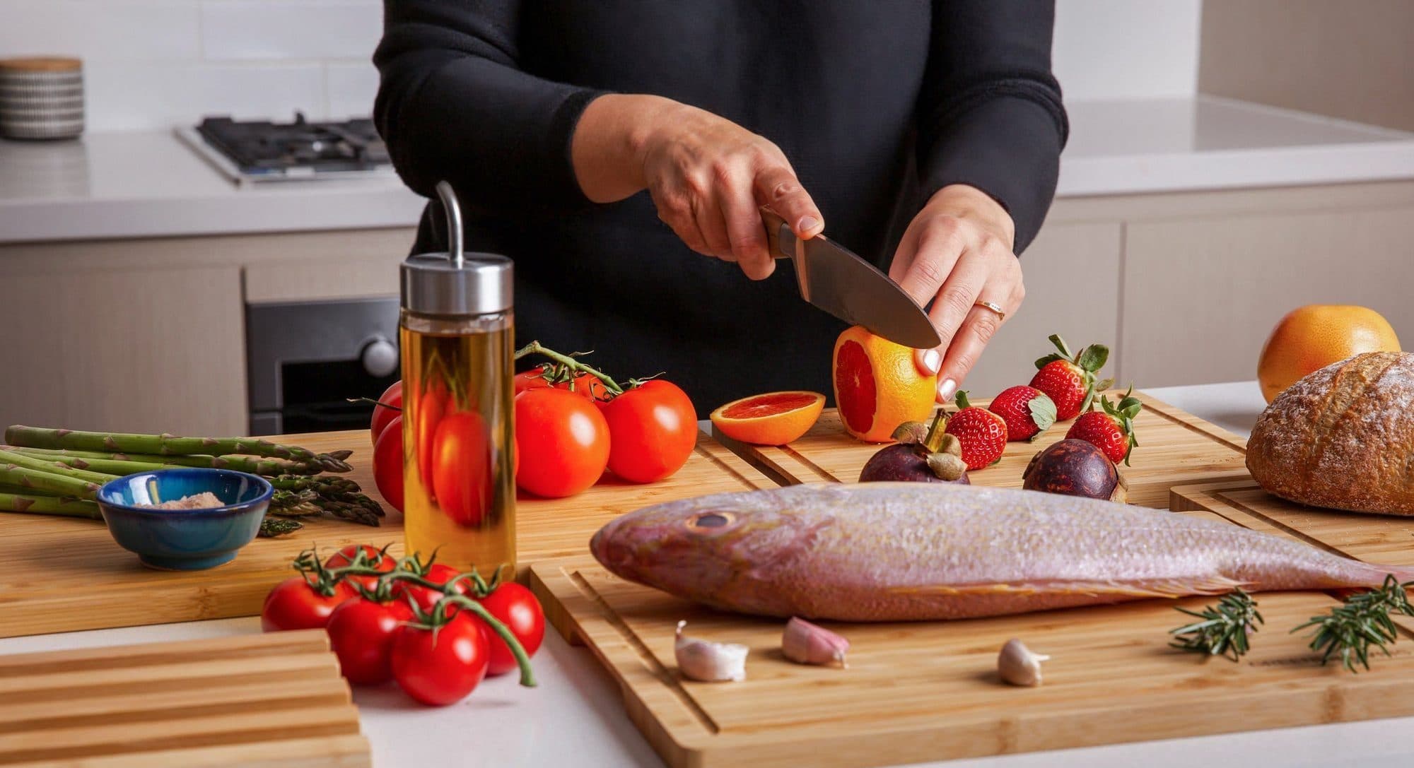 Three bamboo cutting boards laid out with vegetables, bread and raw steak prepared separately