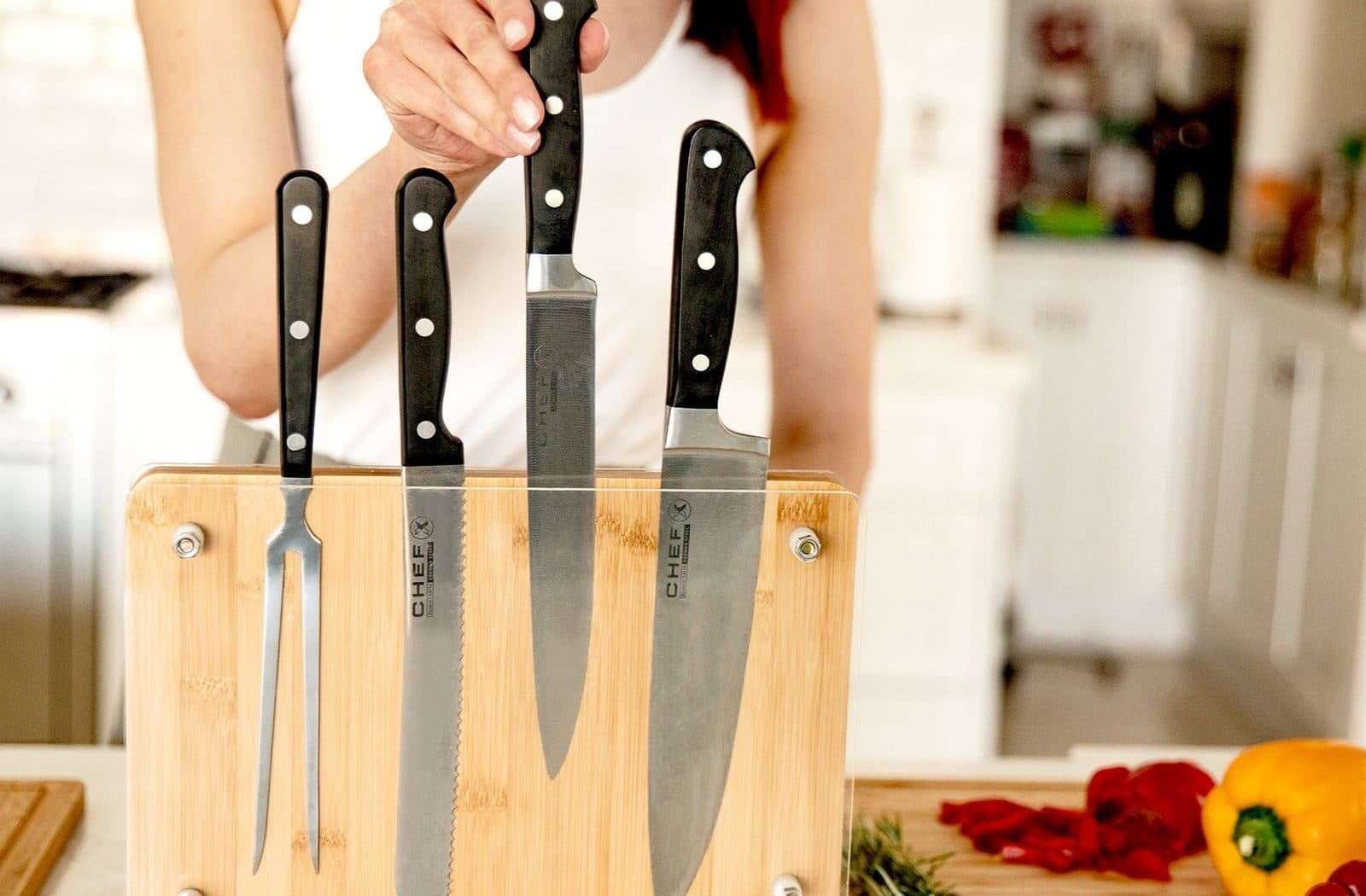 Bamboo magnetic knife holder on a kitchen bench holding a set of knives