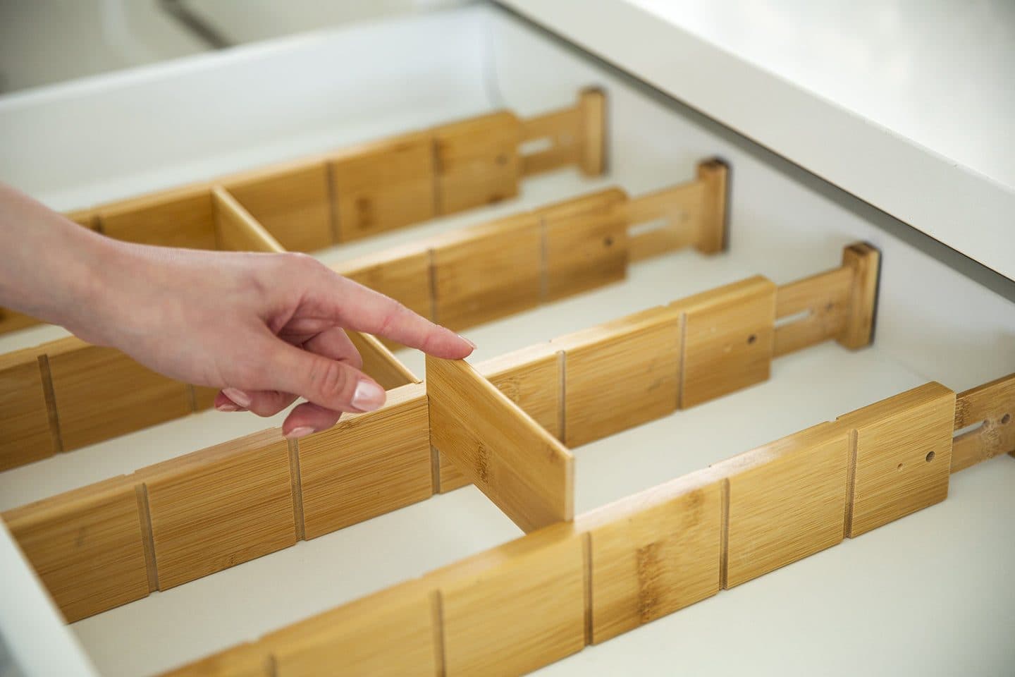 Hand fitting a bamboo divider into a drawer compartment