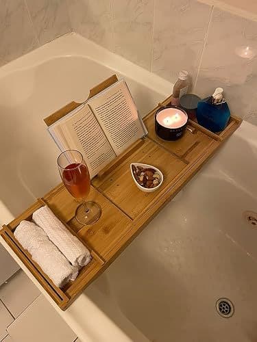Customer photo of the bath caddy set up over a bathtub with a book, candle, wine glass and folded towels