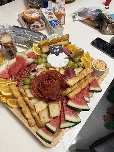 Customer photo of a charcuterie spread arranged on the cheese board, with cured meats, watermelon, grapes and a cheese label tag