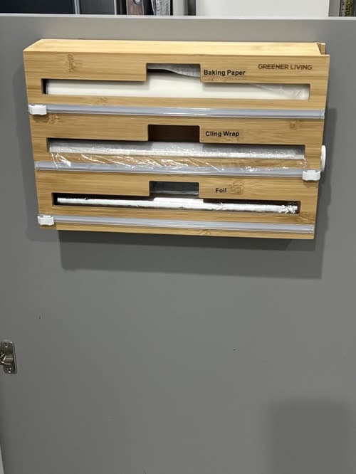 Customer photo of the dispenser wall-mounted and loaded, with the baking paper, cling wrap and foil compartments labelled